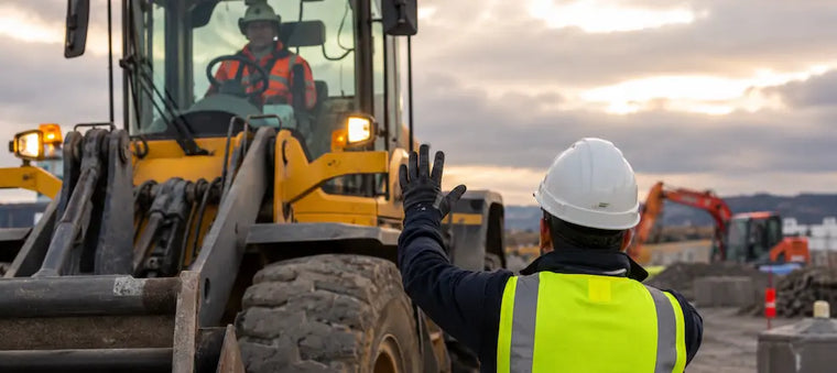Worker signaling a loader operator on a construction site.