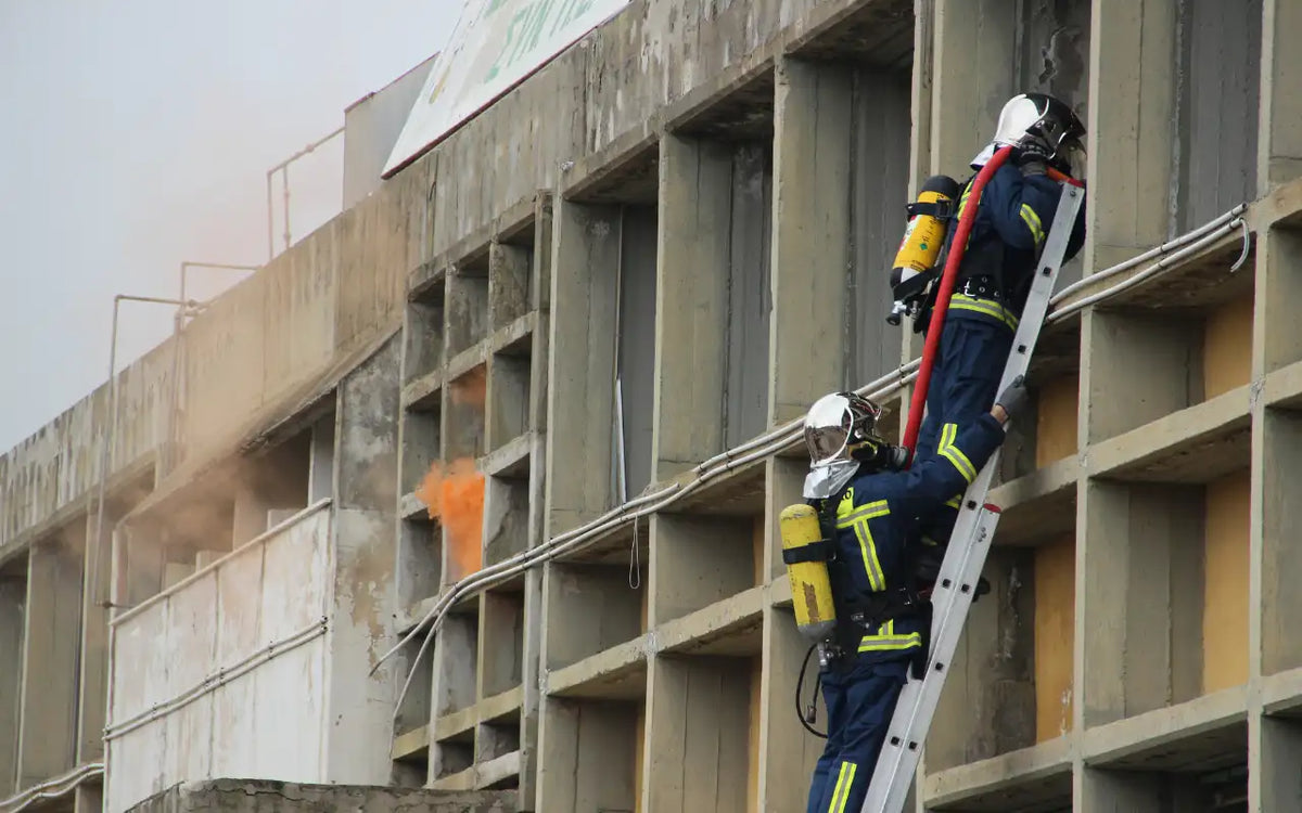 Firefighter performing emergency rescue operation using ladder on a high-rise building.