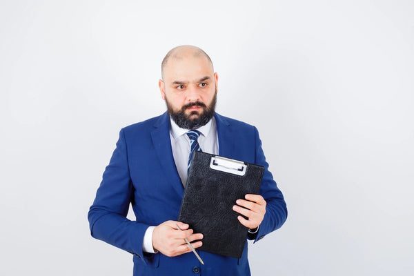 European business professional holding a clipboard and reviewing compliance documents in a clean office setting, representing healthcare data protection and HIPAA business associate responsibilities.