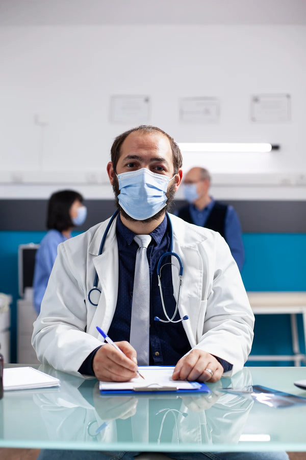 European healthcare professional wearing a lab coat and stethoscope documenting patient information on a clipboard in a modern clinic while following healthcare privacy and compliance practices.