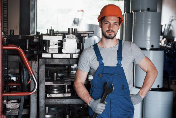 Factory worker wearing hard hat holding wrench in metalworking plant